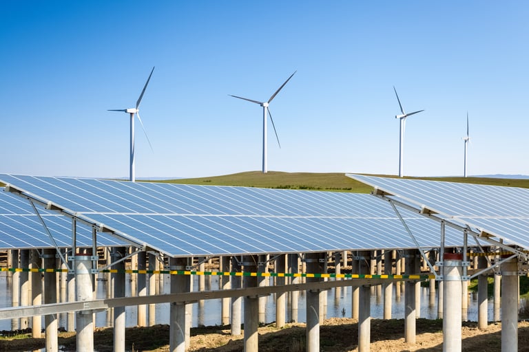 Solar panels and wind turbines producing renewable energy under a clear sky, representing 2025 renewable energy trends in solar, wind, and sustainable power technologies for industrial and commercial growth.